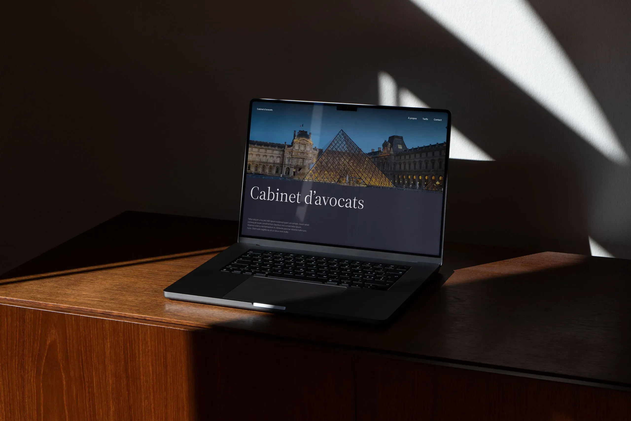 Un ordinateur portable posé sur un meuble en bois élégant qui affiche un site internet pour avocats