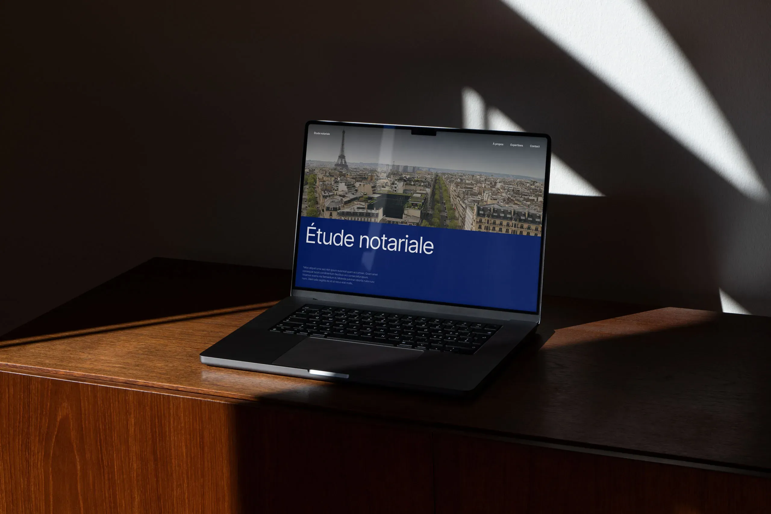 Un ordinateur portable posé sur un meuble en bois élégant qui affiche un site internet pour notaires